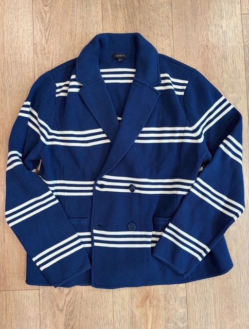 A navy and white striped blazer laid flat on a wood floor