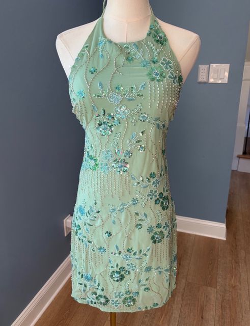 A sage green beaded halter dress on a dress form