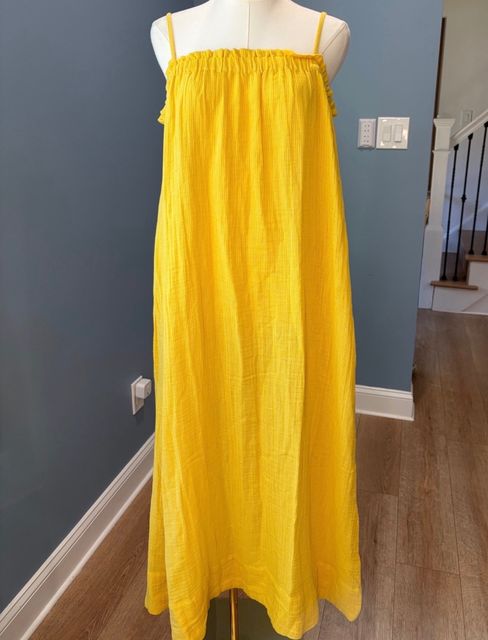 A yellow gauze maxi dress with thin straps on a dress form