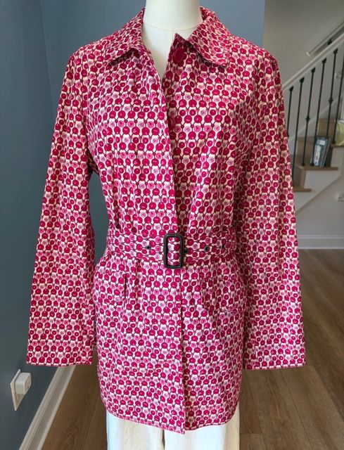 A pink and cream printed belted jacket on a dress form