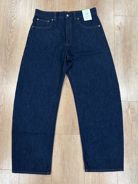 Dark indigo wide-leg jeans with the tags still on, laid flat on a wood floor