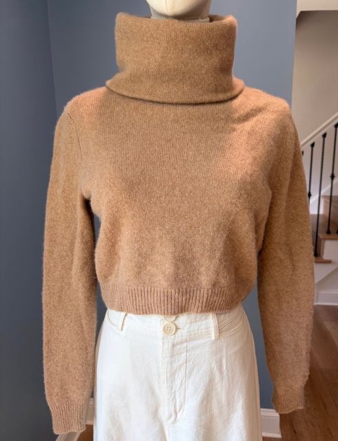 A camel turtleneck sweater over a cream skirt on a dress form